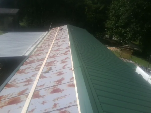 Old rusted panels beside newly installed green metal roofing — Wind Damage Roof Repair by Roofing Brothers in Wymore