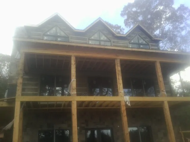 Dormers and porch framing on a large log home under construction — Roof Coating work by our crew in Wymore