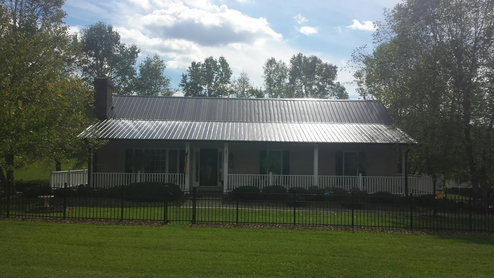 Gray metal roof on a brick ranch with a full width front porch — Gutter Guard Installation work by our crew in Wymore