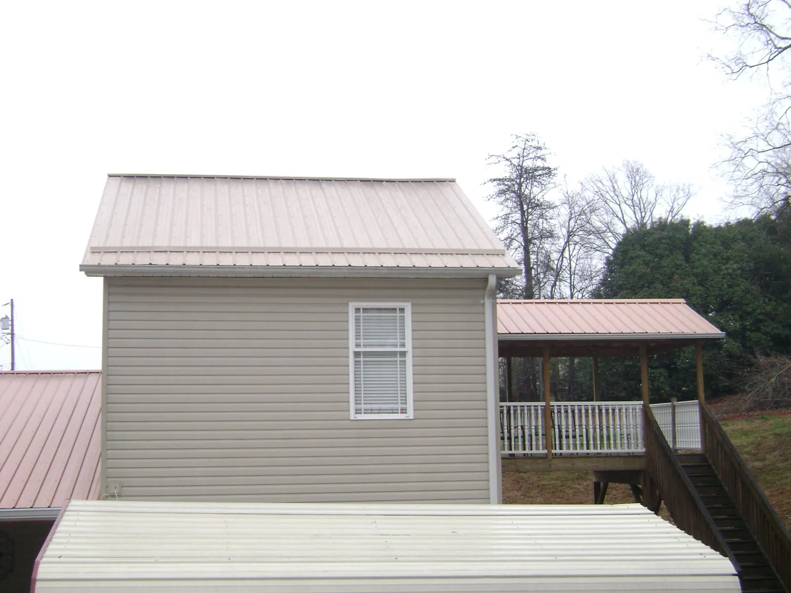 Tan metal roofs on a two story addition and attached porch, from a Roof Replacement job in Wymore