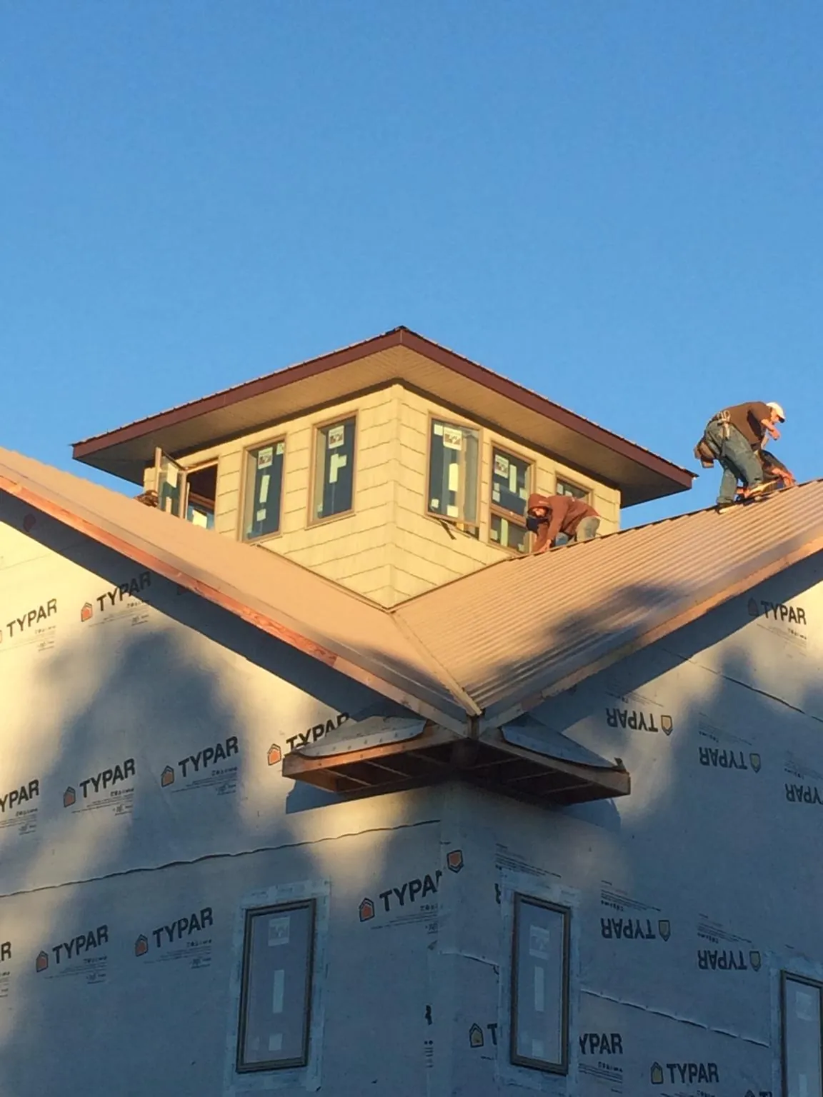 Roofers working around a rooftop cupola on a new metal roof at sunset — Roof Waterproofing in Wymore by Roofing Brothers